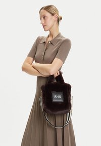 Borsa a tracolla in ecopelliccia marrone con forma rettangolare, dotata di un'etichetta nera con la scritta "LIU-JO". Comprende manici corti e una tracolla regolabile a righe.