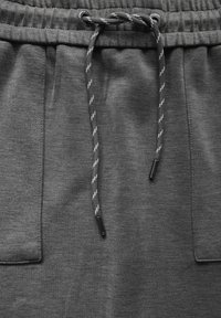 Graue Jogging-Shorts mit elastischem Bund, ausgestattet mit einem Kordelzug und strukturierten Akzenten sowie zwei Fronttaschen. Weicher Stoff.