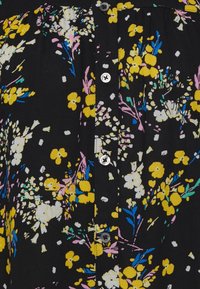 Tissu noir avec des boutons et un motif floral aux couleurs jaune, blanc, rose, bleu et vert.