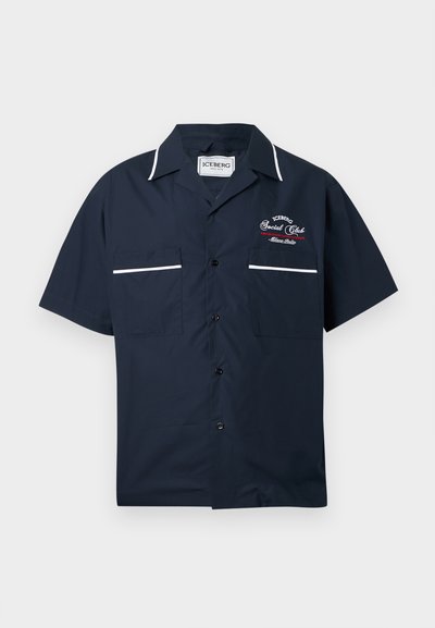 Chemise à manches courtes bleu marine en tissu léger, dotée de deux poches à l'avant, de détails en passepoil blanc et d'un logo brodé.