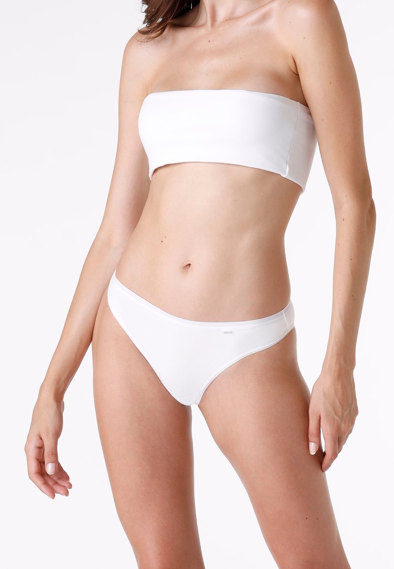 Top a bandeau bianco e bikini coordinato realizzati in tessuto liscio. Design semplice senza motivi o decorazioni visibili.