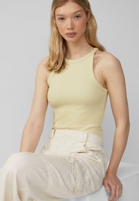 Lichtgele geribde tanktop met een hoge halslijn en brede schouderbanden, gecombineerd met crèmekleurige cargobroek met zijzakken.