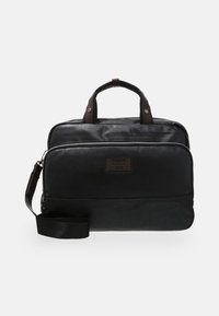 Černá kožená taška na notebook s duálními horními uchy, odnímatelným popruhem, přední kapsou na zip a značkovou nášivkou. Hladká textura, minimalistický design.