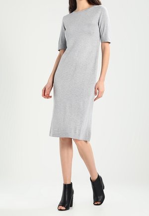 Abito grigio al ginocchio realizzato in morbido tessuto elasticizzato, con maniche corte e scollatura rotonda. Indossato con stivaletti neri alla caviglia.