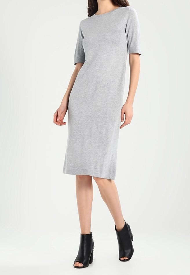 Robe grise midi en tissu doux et extensible, avec des manches courtes et un col rond. Portée avec des bottines noires.