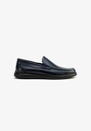 Zapatos slip-on de cuero azul marino con punta redondeada, superficie texturizada y suela de goma negra flexible. Diseño minimalista sin hardware visible.