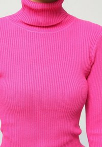 Pull à col roulé ajusté en rose vif. Texture côtelée sur l'ensemble, avec des manches longues et un col haut.