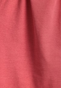 Katoenen stof in een zachte koraalkleur met een licht gestructureerd oppervlak, met natuurlijke plooien en kreuken. Geen patronen of accenten zichtbaar.