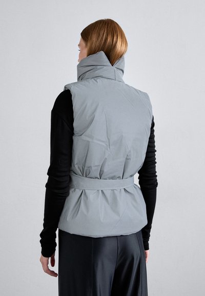 Grå pufferväst med hög krage, åtsittande midja och strukturerad yta. Har en bältad design och mjukt, vadderat material.