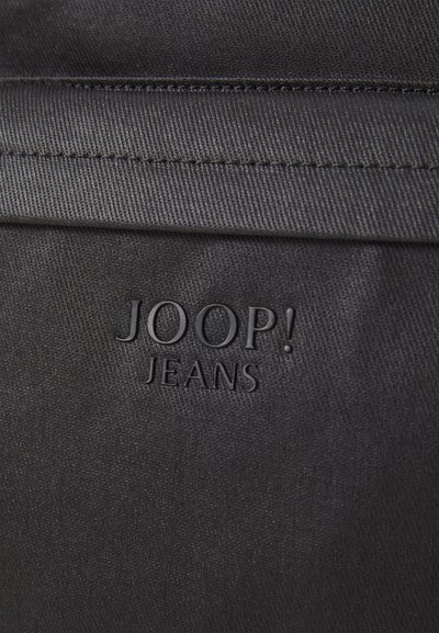 Un tissu noir au toucher lisse présente le logo en relief "JOOP! JEANS" affiché de manière proéminente. Design simple sans motifs ou accessoires supplémentaires.