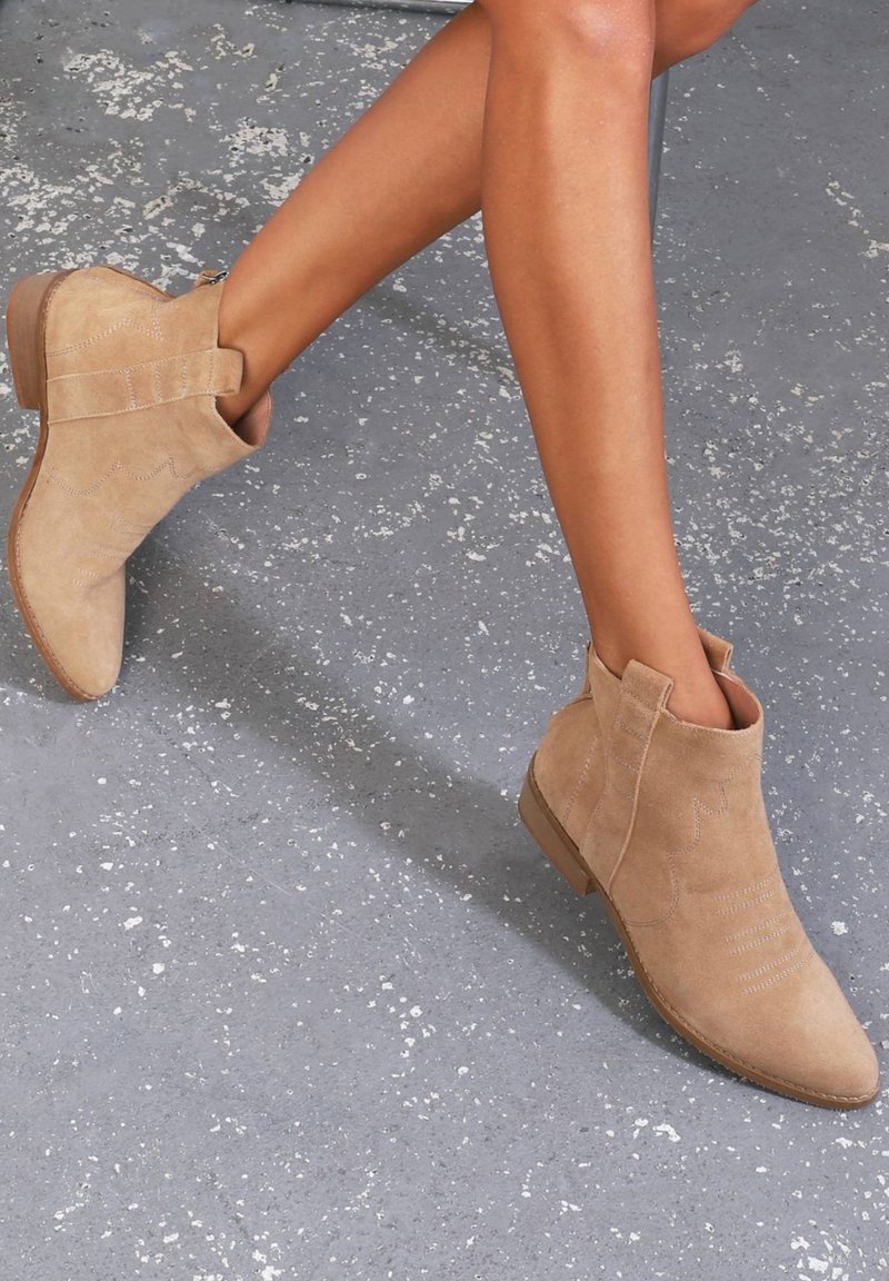 Botines de ante en color beige con detalles de costura, punta afilada y un tacón bajo apilado. Idóneos para un estilo casual.