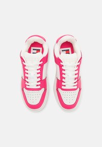 Baskets roses et blanches avec une tige lisse en synthétique, une boîte à orteils perforée, des lacets plats et un logo sur la languette. Semelle arrondie et rembourrée.