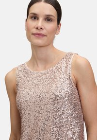 Różowo-złoty bezrękawnik pokryty cekinami, z okrągłym dekoltem i teksturowaną powierzchnią. Lekka i dopasowana forma.