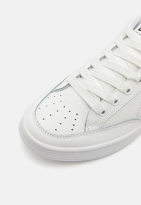 Vita lädersneakers med rund tå, gummisula, slät yta och perforerat detaljer på ovandelen. Snörningsdesign med platta skosnören.
