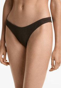 Slip de bikini texturat maro, cu un design cu talie joasă, dotat cu un brâu lat și o acoperire minimă, evidențiind un material împletit.