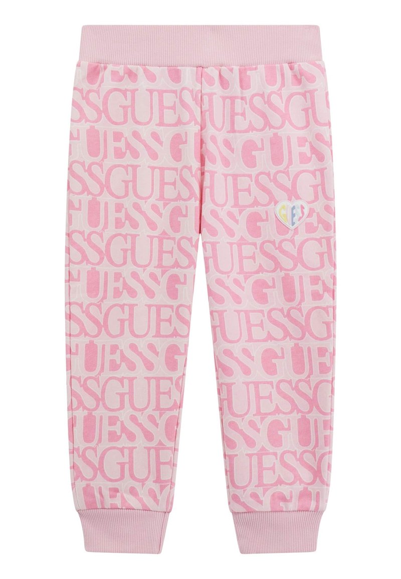 Pantalons de survêtement roses avec un motif de logo "GUESS" répété, une taille et des poignets côtelés. Petit logo en forme de cœur multicolore sur le côté.