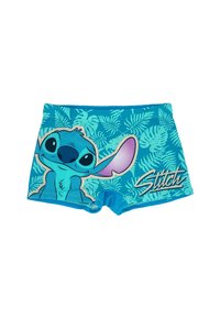 Shorts de bain bleus avec un personnage de dessin animé aux grandes oreilles. Le design comprend des motifs de feuilles vertes et le mot "Stitch" en blanc.