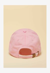 Gorra de béisbol de algodón rosa vista desde atrás con correa ajustable y fondo beige.