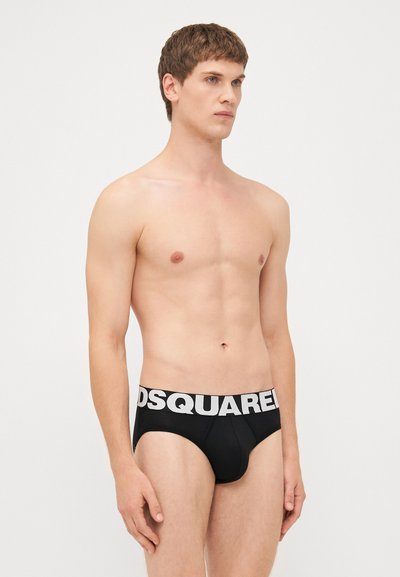 Schwarze Baumwollunterwäsche mit einem weißen elastischen Bund, auf dem das Logo "DSQUARED2" zu sehen ist. Enganliegendes Design, glatte Textur und minimale Abdeckung.