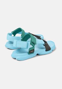 Blue sandals with adjustable teal and black straps, made of durable materials, featuring a contoured sole and textured accents.