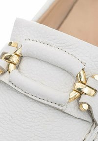 Witte leren loafers met een textuurafwerking, gouden hardware en een decoratieve band met een lusdetail. Ontwerp met een platte zool.