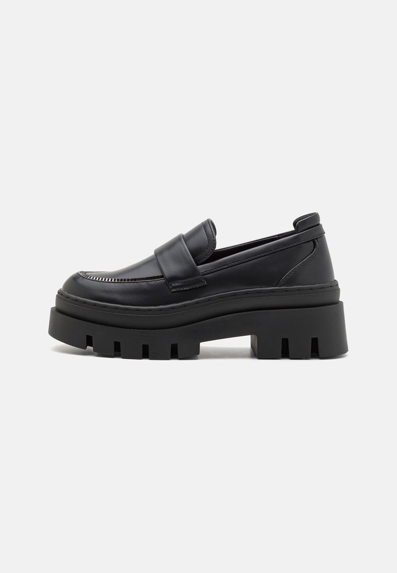 Mocassins en cuir noir avec une semelle plateforme épaisse, présentant des coutures détaillées et une large bride sur le cou-de-pied. Design solide et robuste.