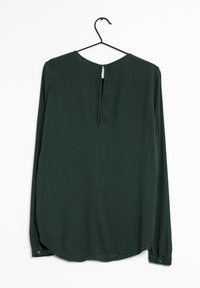 Blusa a maniche lunghe di colore verde scuro appesa a un gancio nero. Presenta un collo rotondo con un'apertura a forma di chiave e polsini con bottoni. Tessuto liscio.