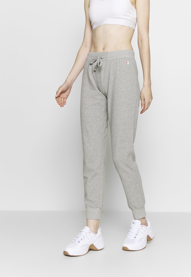 Gray sweatpants with a fitted design, drawstring waist, and elastic cuffs, paired with white athletic shoes. Smooth fabric texture.