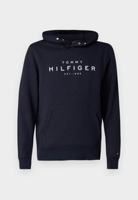 Felpa navy blue di Tommy Hilfiger con tasca frontale, cappuccio con bottoni a pressione e testo logo bianco "TOMMY HILFIGER EST. 1985" sul petto.