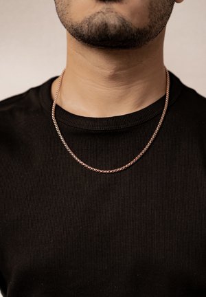 Silver chain necklace displayed on a person wearing a black ribbed shirt. Necklace features a twisted design, medium thickness, and uniform links.
