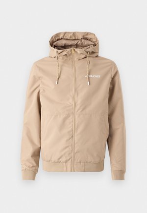 Beige Zip-Jacke mit Kapuze, Kordelzügen, elastischen Bündchen und Saum. Auf der linken Brustseite befindet sich das "JACK&JONES"-Logo in Weiß.