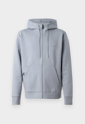 Grå hettejakke med en jevn tekstur, hette, to frontlommer, og ribbede mansjetter. Har et lite brodert logo på brystet.