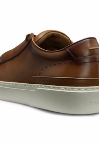 Brązowe skórzane sneakersy o gładkiej fakturze, z delikatnym akcentem na pięcie i grubą białą podeszwą z bocznymi przeszyciami.