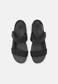 Sandali neri con doppie cinghie regolabili, dotati di una soletta in schiuma yoga e una suola piatta in gomma, progettati per il comfort e una facile indossabilità.