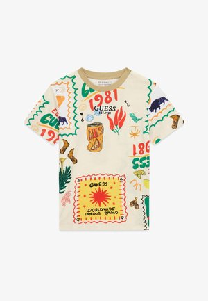 Beżowy T-shirt z krótkim rękawem z kolorowymi bazgrołami, w tym puszką, czerwonymi papryczkami chili, butami, słońcem i napisem "Guess 1981".