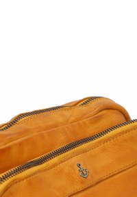 Bolso de cuero de color amarillo brillante, que cuenta con dos compartimentos con cremallera, una textura suave y un detalle de ancla grabado en el lateral.