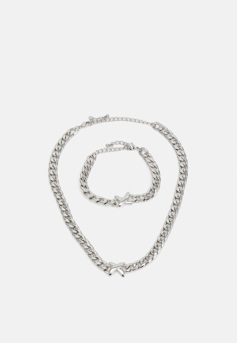 Srebrna verižica in zapestnica, ki vključujeta debelo linkasto zasnovo z zvezdastim poudarkom. Gladka tekstura, poliširana končna obdelava, nastavljive dolžine.