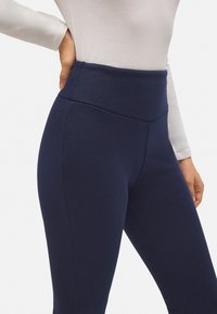 Leggings de cintura alta en color marino, hechos de una tela texturizada con un acabado suave. Presentan una cinturilla sin costuras y un diseño ajustado.
