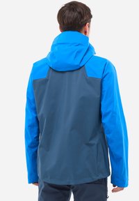 Wasserdichte Jacke mit einer blauen Kapuze und Oberkörper sowie einem dunkelgrauen unteren Abschnitt, glatter Textur und verstellbaren Funktionen.
