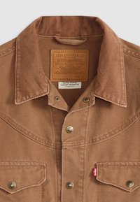 Bruine corduroy shirt met een puntkraag, twee borstzakken, metalen knopen en een leren merklabel. Heeft een zijlabel met logo.
