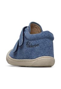 Blue denim shoe with a soft, textured upper, rounded toe, and a flexible rubber sole. Features a lace at the ankle and embroidered logo.