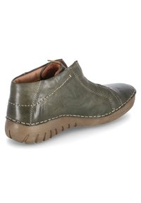 Scarpa in pelle verde con punta arrotondata, dettagli cuciti, tacco basso e suola in gomma texturizzata. Interno foderato in tessuto marrone.