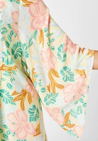 Kimono con estampado floral que presenta mangas anchas y fluidas. La tela tiene un aspecto suave y texturizado con colores pastel en rosa, verde y amarillo.