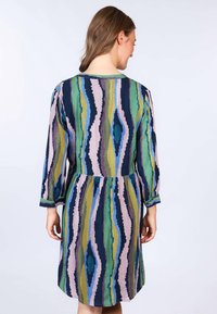 Mehrfarbiges Kleid mit Zickzackmuster in Blau, Grün, Pink und Marineblau. Es hat lange Ärmel und eine geraffte Taille.