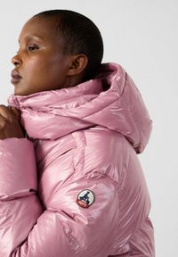 Roze gevoerde jas met hoge kraag en capuchon, met een glanzende textuur en logo-opdruk op de mouw. Duidelijke gestikte details.