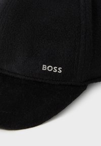 Svart fleece caps med buet skjerm, med en sølv "BOSS" logo foran. Myk tekstur og uformell design.