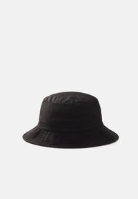 Chapeau seau noir en tissu léger avec une texture douce. Il dispose d'un large bord et d'un motif cousu autour du bord.