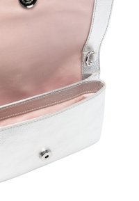Interno di una borsa in pelle argentata che mostra una fodera rosa tenue, chiusura a scatto e tasca interna per l'organizzazione, con una texture liscia e un design elegante.