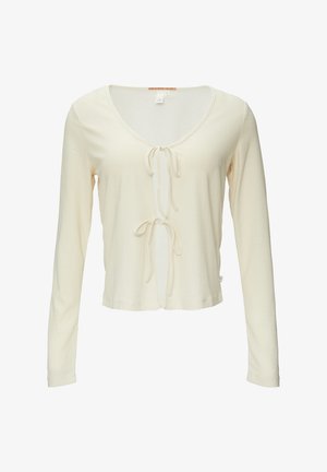 Crème lange mouwen top met een ronde hals en een striksluiting aan de voorkant, gemaakt van een textiel met een lichte, gemêleerde textuur.