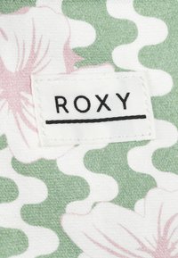 Multicolored fabric features pink flowers on a green background with white wave patterns. A white label displays "ROXY" in black.